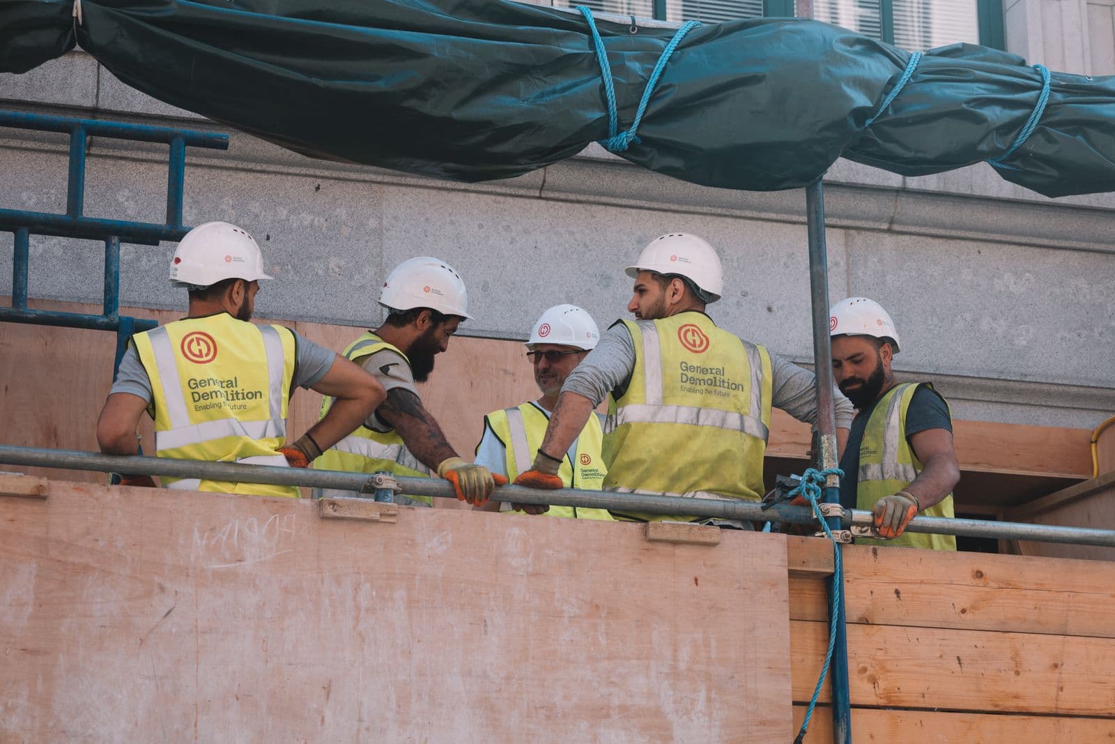 Equipo de pintores con ropa de alta visibilidad y casco en una fachada de Bilbao